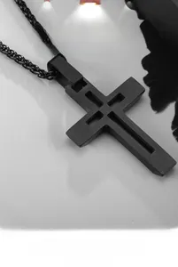 Gros plan du pendentif croix noire mate évidée avec texture de métal brossé