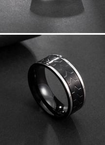 Macro detail of men's titanium ring featuring brushed black steel and arrow pattern