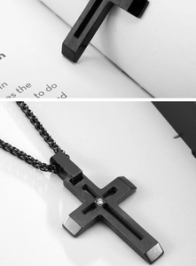 Détail d'un pendentif croix creuse en acier titane noir avec zircon et chaîne tressée