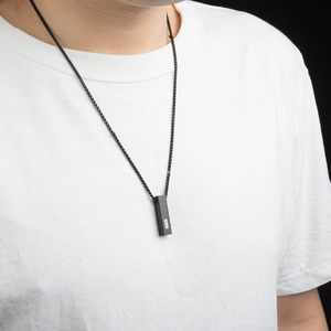 Minimalist matte black stainless steel bar necklace on a white t-shirt for men