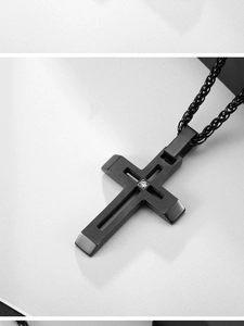 Détail macro du pendentif croix en acier noir mat avec pierre de zircone incrustée