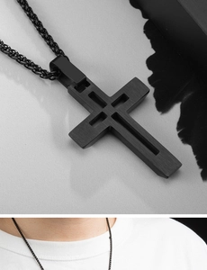 Détail du pendentif croix évidée en acier noir mat avec chaîne tressée sur un modèle