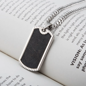 Men's carbon fiber inlay pendant necklace in stainless steel on a vintage book