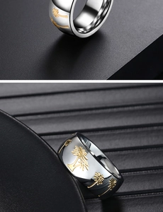 Macro view of wide silver steel band featuring engraved golden palm tree patterns