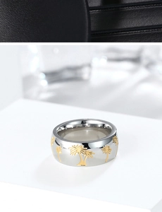 Macro shot of polished steel ring featuring embossed gold tropical palm tree details