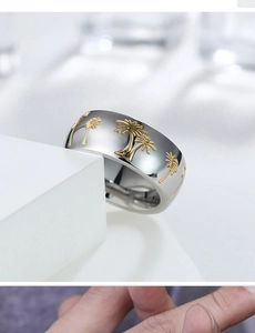 Macro detail of wide stainless steel ring featuring golden coconut tree relief patterns