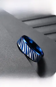 Close-up of titanium steel ring with diagonal blue and silver polished stripes