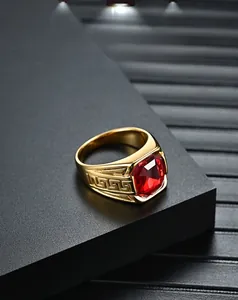 Détail de la bague en acier doré avec pierre précieuse rouge et motif de clé grecque
