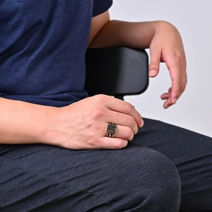 Men's vintage gold ring with square black gemstones and embossed texture on model's finger