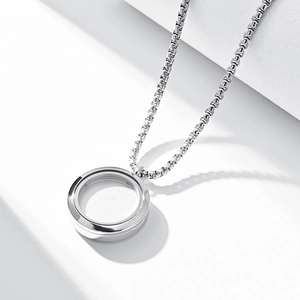 Polished stainless steel round locket pendant on box chain necklace over geometric pedestal