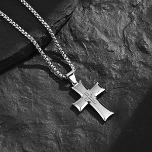 Silver stainless steel cross pendant necklace with small crystals on a black rock background