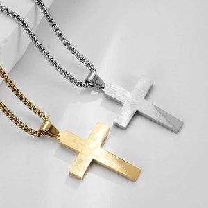 Polished gold and silver stainless steel cross pendant necklaces on white display