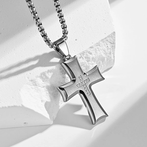 Brushed stainless steel cross pendant necklace with zircon inlay on a white stone background