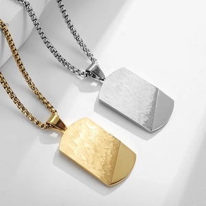 Gold and silver stainless steel faceted military dog tag necklaces on a white stone background