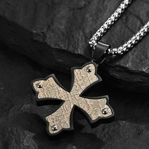 Collier croix gothique en acier inoxydable noir et bronze sur fond de roche sombre