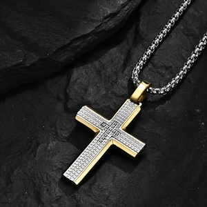Collana a croce da uomo in acciaio inox con bordo dorato e strass su sfondo di roccia
