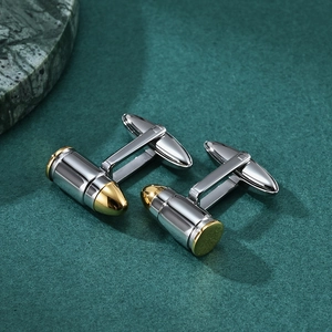 Polished silver and gold bullet cufflinks for men's shirts on a textured green background