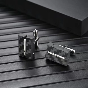 Boutons de manchette rectangulaires en fibre de carbone et métal argenté sur fond en cuir noir