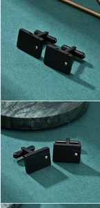 Detail of square black stainless steel cufflinks with geometric lines and tiny crystal inlay