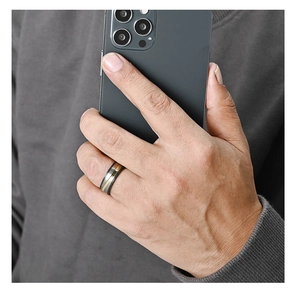 Close-up of men's matte grey titanium ring with rose gold inlay held against a phone