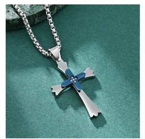 Gros plan du pendentif croix en acier inoxydable double couche avec placage bleu et pierres