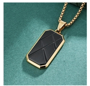 Macro detail of gold box chain and black geometric octagonal pendant on green leather