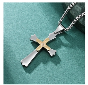 Détail d'un pendentif croix bicolore avec quatre pierres sur une chaîne maille vénitienne