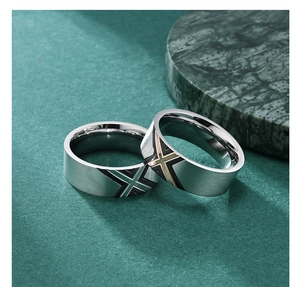Detail of brushed titanium steel rings in green and gold with cross pattern