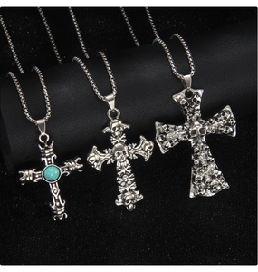 Détail de pendentifs gothiques en forme de crâne et de croix en argent vieilli sur fond noir