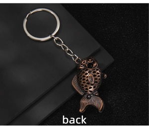Detailed back view of vintage bronze fish keychain with hollowed-out metal texture