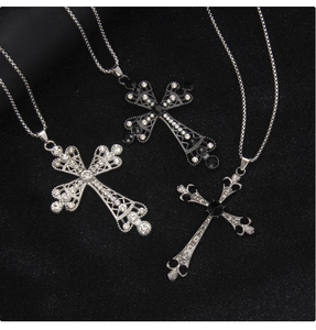 Detail of three punk style stainless steel cross pendants with rhinestones on black display