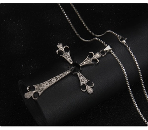 Detail view of gothic cross necklace with black gemstone and intricate floral engraving
