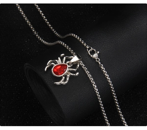 Macro shot of punk spider necklace with red gemstone drop on black leather