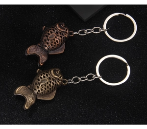 Macro shot of two vintage koi fish keychains in antique bronze and copper finish