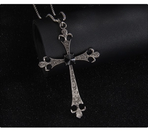 Macro view of gothic silver cross necklace with black gemstone on leather roll