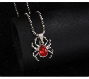 Close-up of gothic spider pendant with red teardrop stone on black leather stand