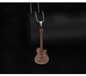 Close-up of a vintage bronze guitar pendant with music engraving on a silver chain