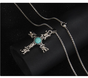 Gros plan du pendentif croix gothique en argent avec turquoise sur support à bijoux