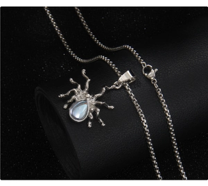 Macro shot of a punk spider pendant with a light blue gem on a dark leather surface