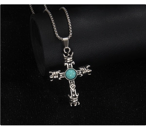 Gros plan détaillé du pendentif croix en argent gravé avec pierre turquoise centrale