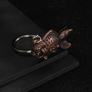 Vintage bronze carp keychain with detailed scales and silver metal ring on black background