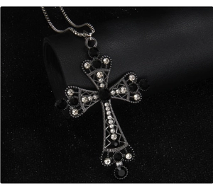 Close-up of vintage gothic cross necklace with black and white crystals on snakeskin chain