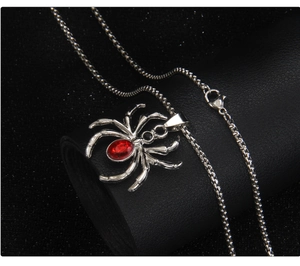 Detail shot of a gothic silver spider pendant with red gemstone on black leather roll