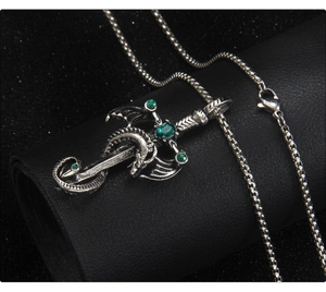 Detail of vintage dragon wrapped around a sword pendant with green gems on leather