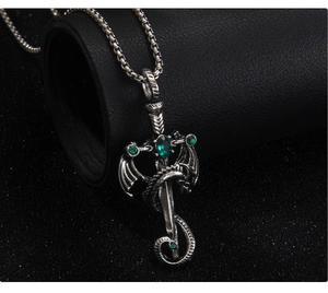 Macro shot of gothic dragon sword pendant with green crystal and box chain on black leather