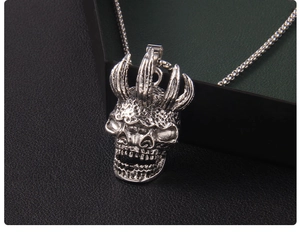 Gros plan d'un pendentif crâne punk rétro avec cornes sur un support d'exposition vert