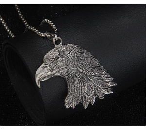 Gros plan détaillé du pendentif tête d'aigle avec plumes texturées sur fond de cuir noir