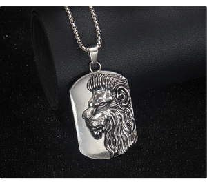 Détail du relief de tête de lion sur un pendentif carré en acier avec chaîne maille box