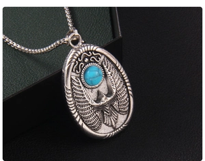 Gros plan du pendentif aigle rétro avec pierre bleue et finition en argent antique