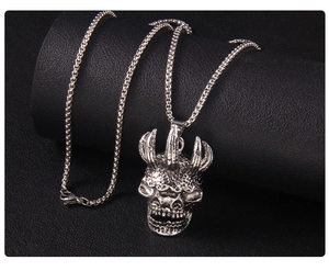 Détail d'un pendentif crâne gothique argenté avec écailles et chaîne box en métal